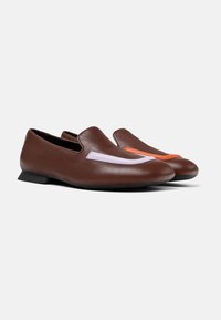 Zapatos de piel marrón de tipo slip-on con tacón bajo, que presentan acentos en contraste de color púrpura claro y naranja en la parte delantera. Textura suave, diseño minimalista.