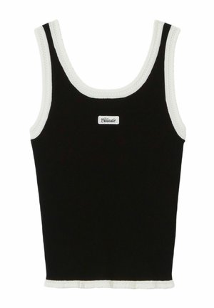 Jeune femme portant une casquette blanche, un top noir sans manches, un pantalon beige à jambes larges et tenant un sac cabas blanc avec des poignées noires ondulées.