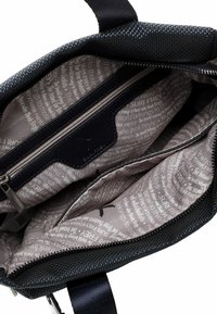 Melns auduma rokassomu ar rāvējslēdzēju; iekšpuse oderēta ar gaiši brūnu materiālu, uz kura ir drukāts teksts. Ietver papildu rāvējslēdzēja kabatu.