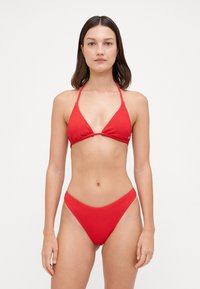 Crveni bikini set koji uključuje teksturiranu trokutastu majicu s tankim trakama i odgovarajuće donje dijelo s niskim strukom, oboje u glatkom pletenom materijalu.