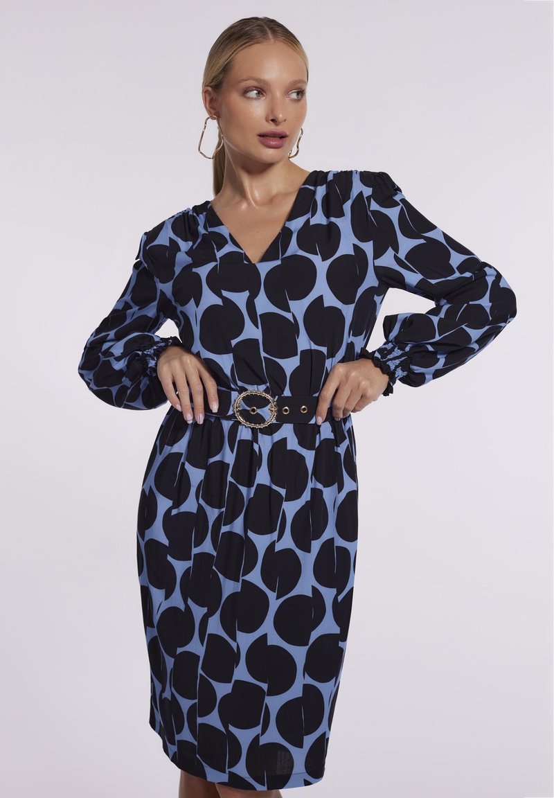 Niebieska i czarna sukienka w wzory z dekoltem w serek, długimi bufkami, elastycznymi mankietami oraz czarnym paskiem z okrągłą klamrą.