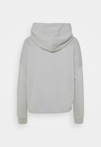 Felpa grigia con una texture morbida, dotata di un grande cappuccio, spalle scese e polsini a costine. Nessun motivo o dettaglio hardware visibile.