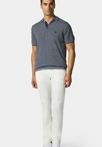 Poloko s límečkem v námořnické a bílé pruhované barvě, přiléhavý střih, krátké rukávy, spárované s bílými kalhotami a bílými teniskami.