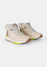 Botas de tobillo beige con cuello de pelo sintético, patrón texturizado, herrajes plateados y acentos amarillos sobre una suela blanca y marrón. Cremallera en un lado.
