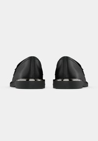 Mustad musta nahast loaferid suju töödeldud pinnaga, ümar varvas, lapik kummitald ja metallilised aktsendid kandadel.