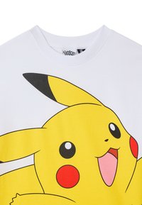 T-shirt bianco in cotone con una grande grafica di Pikachu colorato, con corpo giallo, strisce nere e guance rosse. Collo a giro.