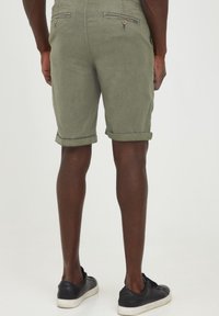 Pantaloni corti verdi khaki realizzati in tessuto leggero, con risvolti, tasche posteriori con chiusura a bottone e un taglio casual.