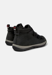Scarpe alte nere con un design testurizzato e suole grigie. Le caratteristiche includono lacci elastici e un colletto imbottito per il comfort.