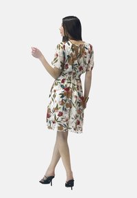 Robe fleurie à manches courtes, taille élastique et détail de dos en forme de keyhole. Présente un fond blanc avec des motifs floraux multicolores.