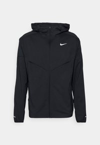 Czarna bluza Nike z kapturem, zapinana na zamek, z białym logo swoosh na klatce piersiowej, elastycznymi mankietami i przednimi kieszeniami, zaprezentowana na jednolitym tle.