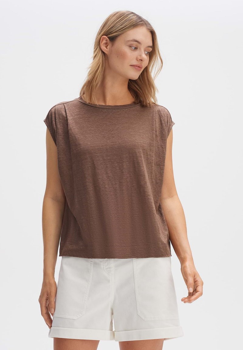 Bruine, kort-gevleugelde top met een ronde halslijn, zachte textuur en een losse pasvorm. Gekoppeld aan witte shorts met opgerolde zoom.