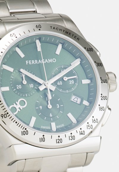 Náramkové hodinky Ferragamo strieborné s tachymetrom, zeleným ciferníkom, tromi subcíferníkmi, dátumovým okienkom na 4. hodine a kovovým náramkom.
