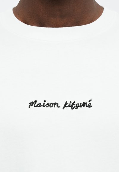 White sweatshirt featuring black embroidered text reading "Maison Kitsuné" near the neckline. Soft fabric with a crew neck design.