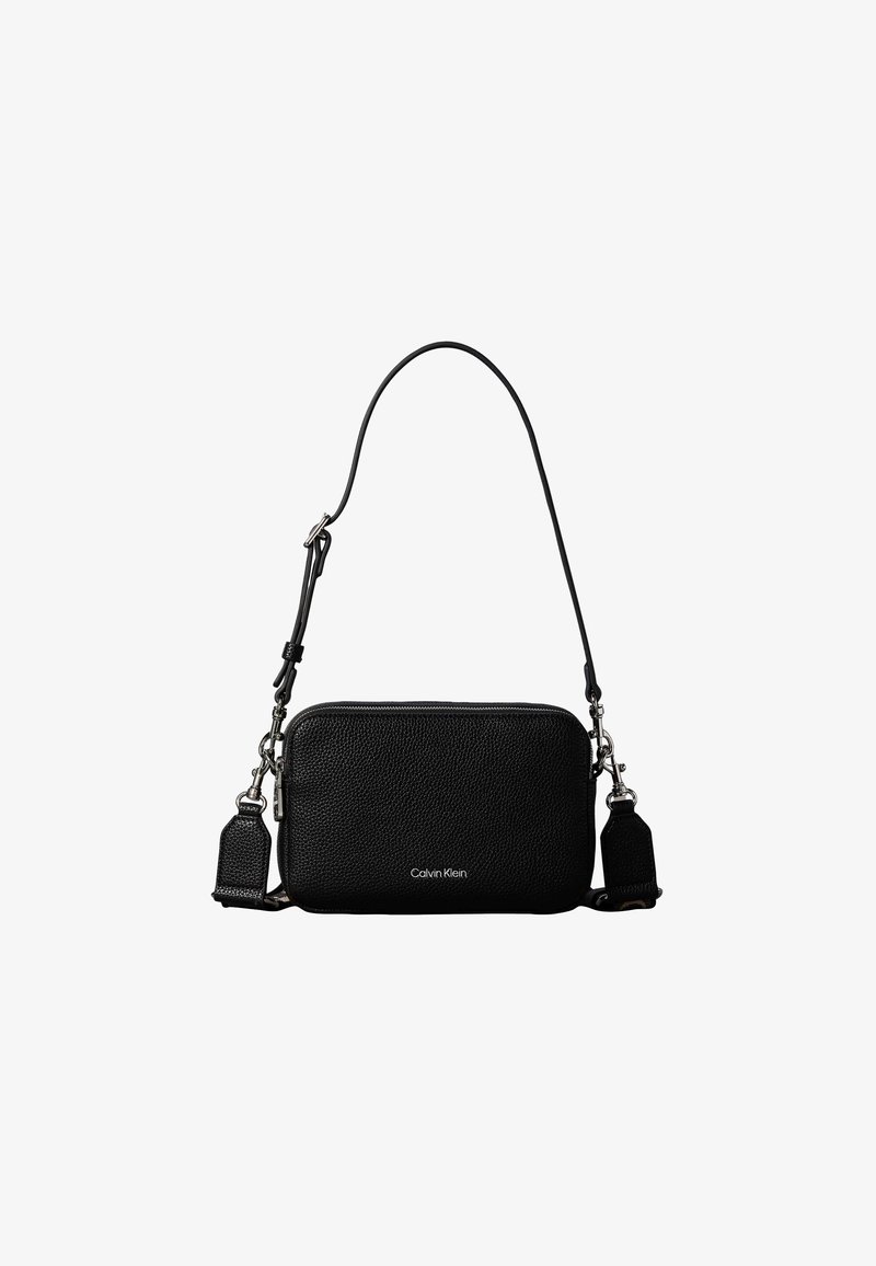 Μαύρη παραλληλόγραμμη τσάντα Calvin Klein για crossbody από δέρμα με υφή, με φερμουάρ στην κορυφή, και ρυθμιζόμενο ιμάντα ώμου, σε λευκό φόντο.