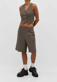 Braune karierte Weste mit kurzem Schnitt und drei vorderen Knöpfen, kombiniert mit passenden knieumspielenden Shorts mit Seitentasche.