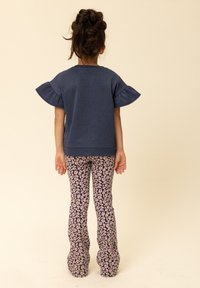 Navyblauw topje met gerimpelde mouwen, gecombineerd met wijde broek met patroon en roze en paarse bloemaccenten. Zachte stof, casual design.
