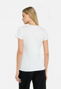 Hvid bomulds t-shirt med korte ærmer og rund hals, glat tekstur og klassisk pasform, vist fra ryggen mod en neutral baggrund.