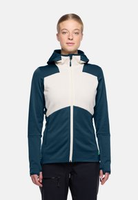 Hoodie met een lichtbeige bovenlichaam en donkerteal onderste secties; textielstof en ritssluiting met zakken.