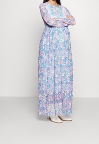 Kwiatowa sukienka maxi z długimi rękawami, w niebieski, różowy i biały wzór, uszyta z lekkiej tkaniny. Gładka, płynąca sylwetka.