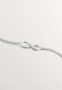 Pulsera de plata con un centro en forma de símbolo de infinito de acabado suave, sobre una cadena delicada con eslabones espaciados uniformemente.