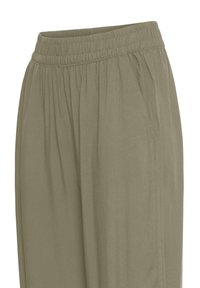 Lahke lõikega oliivrohelised püksid, millel on elastne vöökoht ja küljetaskud, kujutatud vöökohast kuni reie keskosani valgel taustal.