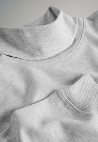 Pull à col roulé gris clair avec col et poignets côtelés, présenté à plat sous un éclairage doux.