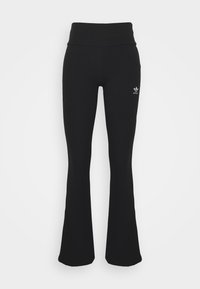 Svarta, ribbade, utsvängda leggings med hög midja och vit Adidas-logotyp på vänster lår. Slät textur, kroppsnära design.