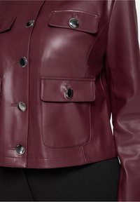 Bordowa skórzana kurtka z srebrnymi elementami, dwoma kieszeniami na piersi i dopasowanym krojem. Gładka faktura z krótkim fasonem.