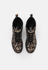 Botas negras hasta el tobillo con un patrón de leopardo en tonos marrones y con detalles metálicos, que incluyen cordones negros y una pestaña en el talón.