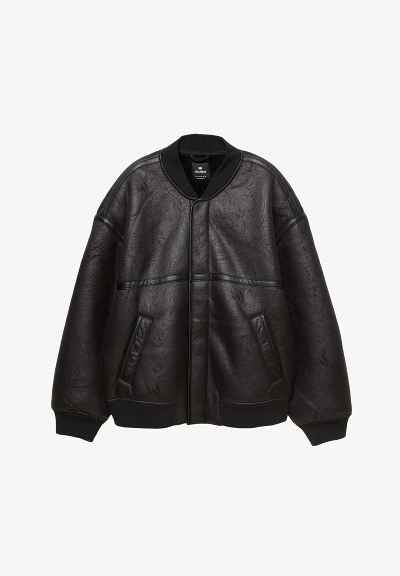 Överdimensionerad svart konstläder bomberjacka med ribbad krage, muddar och nederkant, två framfickor och horisontell läderdetaljering.