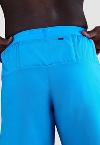 Pantalones cortos de correr azules que presentan un material elástico, una cinturilla elástica con el texto "NIKE RUNNING" y un pequeño detalle de bolsillo en la parte posterior.