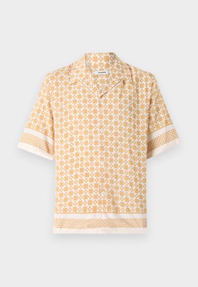 Chemise à manches courtes de couleur jaune clair avec un motif géométrique en crème. Elle présente un devant à boutons et des poignets et un ourlet à motifs contrastants.