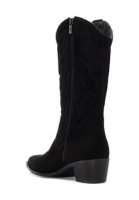 Botas vaqueras de ante negro con puntera afilada, cremallera lateral, costuras decorativas y tacón bajo apilado. Textura lisa con sutiles acentos de patrón.