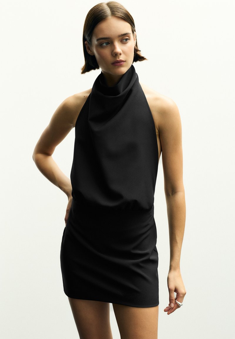 Robe mini noire à col drapé et sans manches, en tissu lisse, avec une taille cintrée et un ruché latéral ajustable pour améliorer la silhouette.