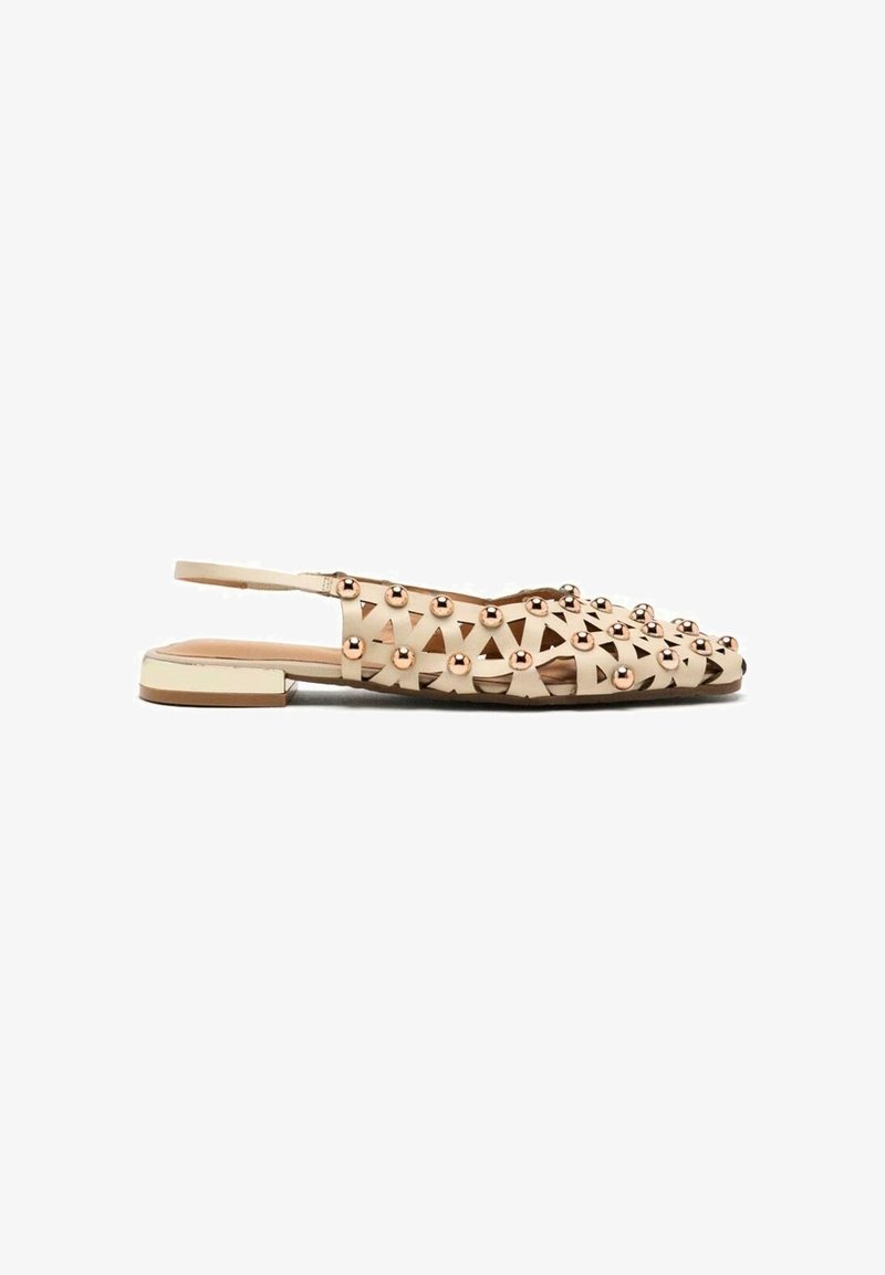 Flats beige à talon plat avec design ajouré et clous métalliques. Bout ouvert et semelle lisse avec une semelle blanche contrastante.