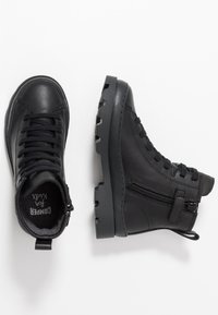 Bottines en cuir noir avec une finition texturée, à lacets à l'avant, fermeture éclair sur le côté, et semelle en caoutchouc dotée d'un design de semelle robuste.