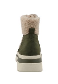 Olivenfarvet ankelstøvle med en fluffy beige krave, der har en tekstureret sål og stilfuld syning langs siden for ekstra detaljer.