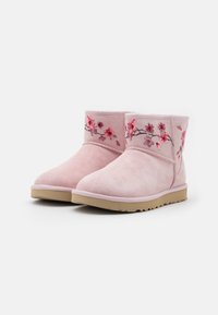 Botas de tobillo de ante rosa con bordados florales en tonos de rosa, que cuentan con una textura suave y una suela de goma beige.