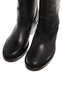 Black leather ankle boots with curved seams, a rounded toe, and a glossy finish. Features a low block heel and reinforced stitching detail.