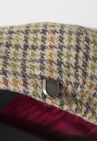 Wool blend cap with a houndstooth pattern in green, beige, and orange, featuring a silver metal logo accent on the side.