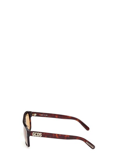 Gafas de sol de patrón carey con lentes marrones y logo de GCDS en blanco en la parte del brazo, vista lateral.