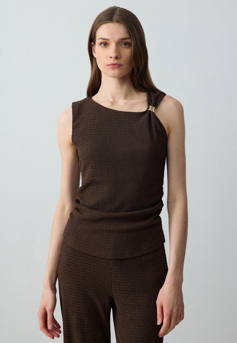 Top sans manches marron en tissu texturé, avec des détails froncés à la taille et un accent doré à l'épaule.