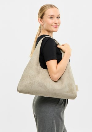 Light gray suede tote bag with a smooth texture, teardrop shape, and wide shoulder strap. Features a subtle brand tag on the side.