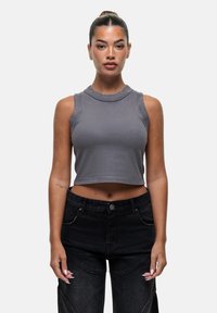 Grijze cropped tanktop met een ronde halslijn en mouwloos ontwerp, gecombineerd met zwarte broek met hoge taille met een strakke textuur en subtiele accentdetails.