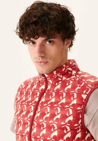 Gilet imbottito con motivo astratto rosso e bianco, colletto alto, zip frontale completa e tessuto grigio chiaro contrastante sui lati.