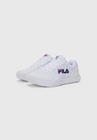 Zapatillas deportivas blancas con parte superior de malla, cierre de cordones y suela acolchada. Presenta el logo de FILA en rojo y azul en el lateral y una suela texturizada.