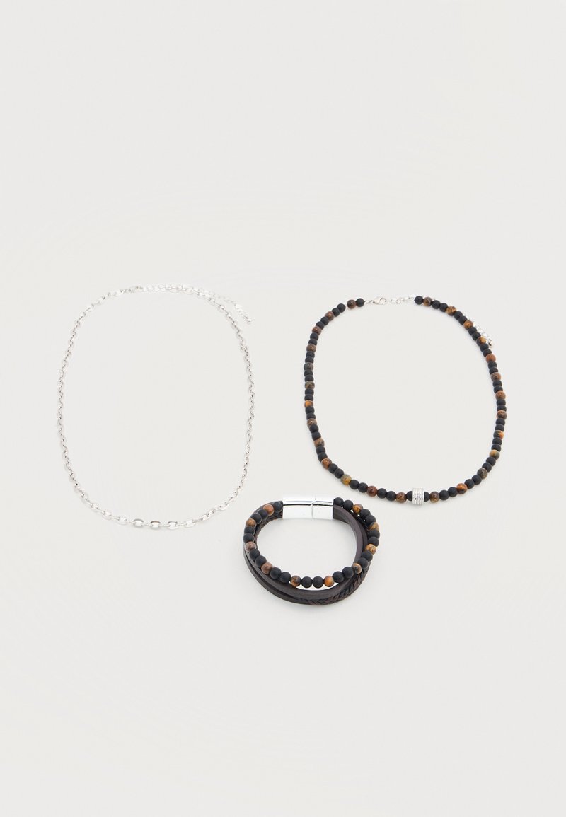 Un collier à chaîne en argent, un collier en perles marron et noires avec fermoir en argent, et un bracelet multi-brins en perles marron et noires.