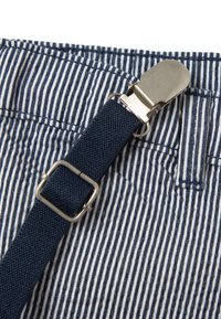 Gestreepte stof in marineblauw en wit, met een metalen clip en gesp, bevestigd aan een kledingstuk, dat een gestructureerd weefpatroon toont.