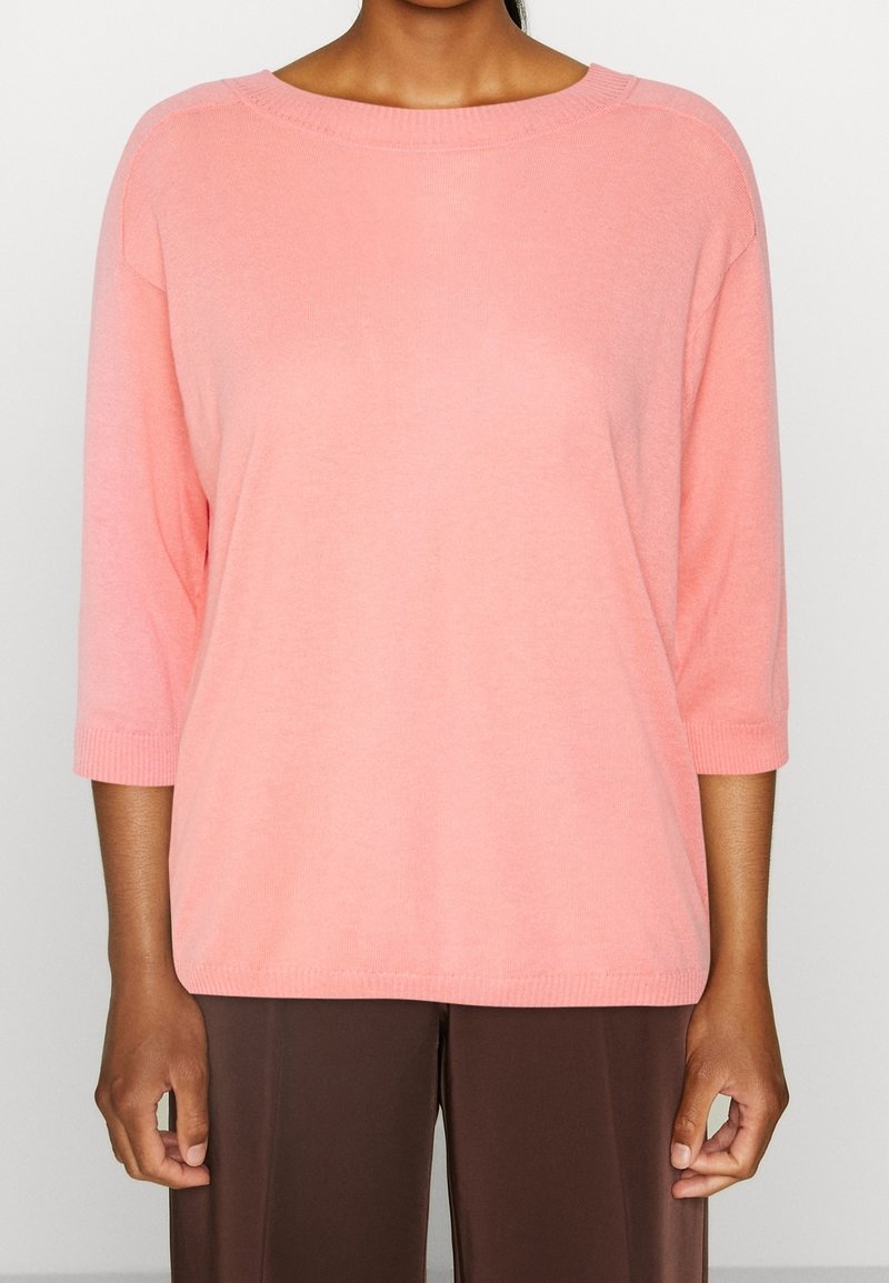 Jasnoróżowy sweter z dzianiny z rękawami do 3/4, okrągłym dekoltem, ściągaczami na rękawach i u dołu, o luźnym kroju i miękkiej fakturze.