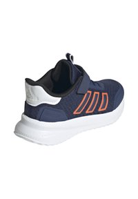Zapatilla deportiva navy con parte superior de malla texturizada, acentos naranjas, una correa de Velcro y una entresuela blanca para amortiguación y soporte.